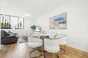a white living room with a table and chairs at Convenient Modern 2Bed Apt Near Airport in Sydney