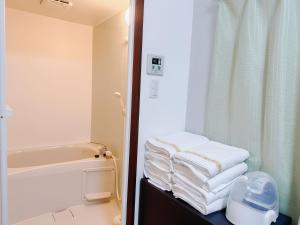 a bathroom with a stack of towels on a table at Retreat Tengachaya 旅趣 天下茶屋 in Osaka