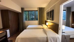 a hotel room with two beds and a window at Hotel Vivenzo Savassi Belo Horizonte in Belo Horizonte