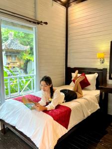 a woman laying on a bed reading a book at Tarci Bungalows Lembongan in Nusa Lembongan +58 photos