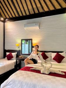 a woman sitting on a bed in a room at Tarci Bungalows Lembongan in Nusa Lembongan