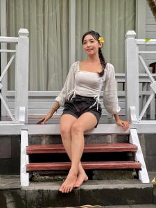 a woman sitting on the steps of a house at Tarci Bungalows Lembongan in Nusa Lembongan