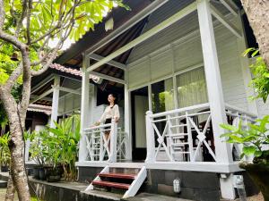 a woman standing on the porch of a house at Tarci Bungalows Lembongan in Nusa Lembongan