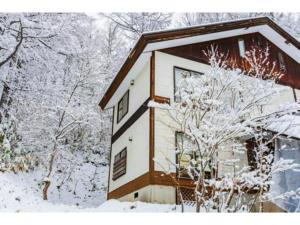 ein schneebedecktes Haus mit Bäumen im Hintergrund in der Unterkunft La Colina Retreat - Vacation STAY 07222v in Madarao Kogen