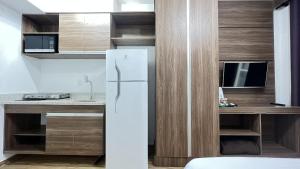 Il comprend une cuisine équipée d'un réfrigérateur blanc et une télévision. dans l'établissement MH 20206 - Lindo Studio com AC/Wi-Fi/Cama Queen, à São Paulo
