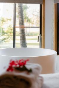 een badkamer met een wit bad en een raam bij Lake Weyba Cottages Noosa in Peregian Beach