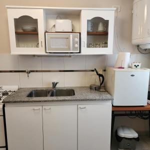 a kitchen with white cabinets and a sink and a microwave at La constancia in La Plata +3 photos