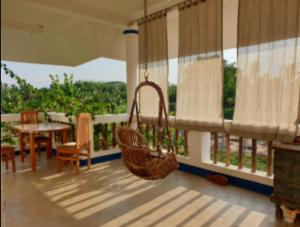 weranda z huśtawką, stołem i krzesłami w obiekcie Tranquility Guest House w mieście Srirangam
