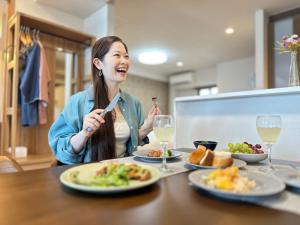 una mujer sentada en una mesa con platos de comida en Garland Court Usami Private Hot Spring Condominium Hotel, en Ito