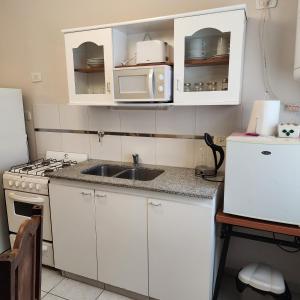 cocina con armarios blancos, fregadero y microondas en La constancia en La Plata