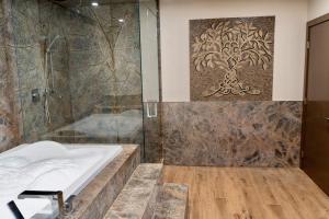 a bathroom with a shower and a bath tub at Luxury suite with Sauna and Spa Bath - Elkside Hideout B&B in Canmore