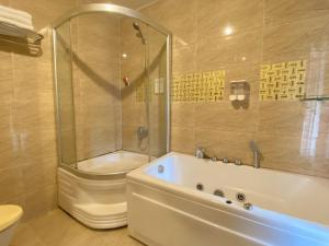 a bathroom with a tub and a shower and a toilet at CROWNE BUI VIEN Hotel in Ho Chi Minh City