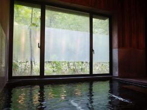 a room with a swimming pool in front of a window at Yamano Hidaya in Matsumoto