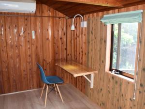 a desk and chair in a room with wooden walls at Tonosaki Bungalow & BBQ in Tsushima