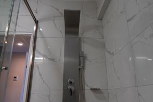 a shower with white marble walls and a glass door at MIRAFLORES CITY HOTEL in Lima