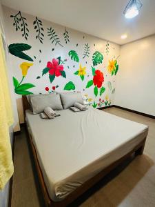 a bedroom with a bed with flowers and leaves on the wall at Jhunbelle in Coron