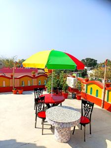 - une table et des chaises avec un parasol coloré sur la terrasse dans l'établissement Rabindra Bilas Homestay, à Bolpur