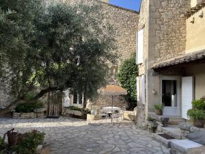 a stone courtyard with a tree and an umbrella at Maison en pierre avec piscine, 6 couchages, située au cœur de Mallemort, Provence. - FR-1-658-25 in Mallemort
