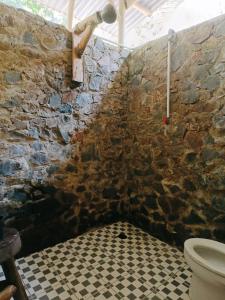 a stone bathroom with a toilet and a checkered floor at back to nature ecotourism in Bukit Lawang