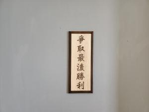 uma imagem emoldurada de escrita asiática numa parede em 55 Hearts Gathering backpacker & B&B em Nangan