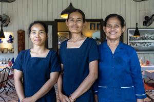 three women in blue uniforms posing for a picture at La Palmeraie D'angkor in Siem Reap +129 photos