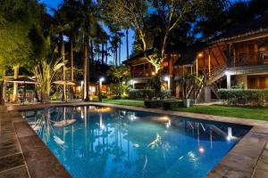 a swimming pool in front of a house at night at La Palmeraie D'angkor in Siem Reap