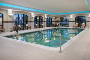 - une piscine dans un hôtel avec des chaises et des tables dans l'établissement Courtyard by Marriott Buffalo Airport, à Cheektowaga