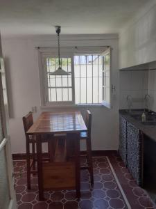 una cocina con una mesa de madera con sillas y una ventana en casa MiLú, en zona Güemes en Mar del Plata