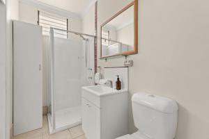 a white bathroom with a toilet and a shower at Kingston Gardens by Experience Jervis Bay in Huskisson