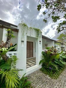 a white house with plants in front of it at Lubdhaka Canggu in Canggu