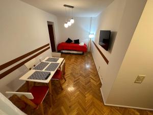 Habitación pequeña con mesa y cama roja. en Cosmopolitan Laprida - Studio in Recoleta en Buenos Aires