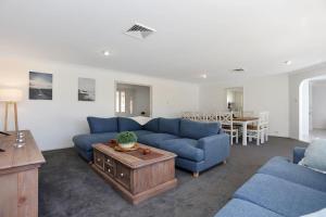 a living room with blue couches and a table at Coastal Calm Pet Friendly in Tea Gardens