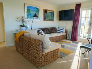 Mangawhai Lodge في مانجاواي: غرفة معيشة بها أريكة وتلفزيون