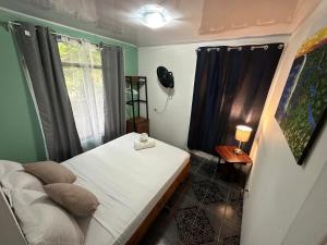 a small room with a bed and a window at Micheck beach house in Tortuguero