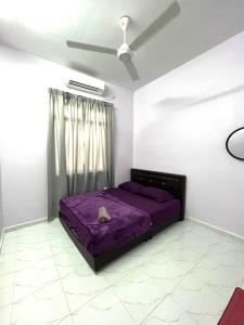 a bedroom with a purple bed and a ceiling fan at Zaf Homestay Pendang in Pendang +2 photos
