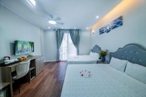 a living room with a bed and a desk and a television at Hanoi Sofia Hotel in Hanoi