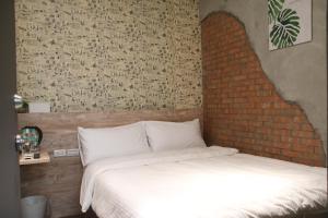 1 dormitorio con cama y pared de ladrillo en Jincheng Hostel, en Changhua County