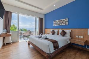 a bedroom with a large bed with a blue wall at The Tanis Beach Resort Nusa Lembongan in Nusa Lembongan
