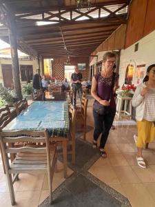 Una donna che cammina intorno a un tavolo in un ristorante di WISMA SIBAYAK Guesthouse BERASTAGI a Berastagi