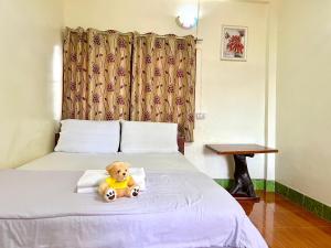 a teddy bear sitting on top of a bed at Khong Chiam Hotel in Khong Chiam