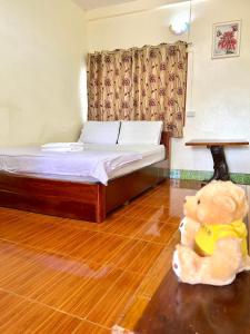 a teddy bear sitting on the floor of a bedroom at Khong Chiam Hotel in Khong Chiam