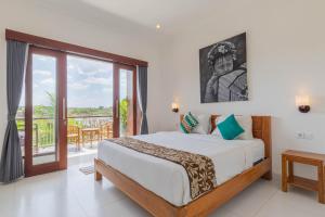 - une chambre avec un lit et un balcon dans l'établissement Frangipani House and Spa by ecommerceloka, à Canggu