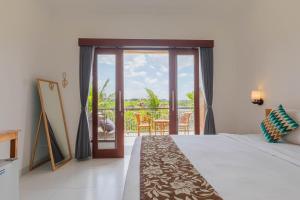 Cette chambre d'hôtel comprend un lit et un balcon. dans l'établissement Frangipani House and Spa by ecommerceloka, à Canggu