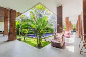 een open lobby met uitzicht op een zwembad en palmbomen bij Frangipani House and Spa by ecommerceloka in Canggu