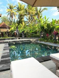 a swimming pool in front of a resort with palm trees at Villa Miracle Ubud in Ubud