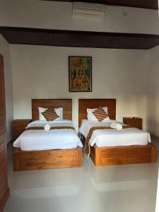two twin beds in a bedroom with a picture on the wall at Villa Miracle Ubud in Ubud