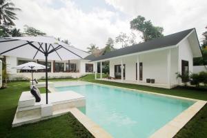 une maison avec une piscine et un parasol dans l'établissement Modern and stylish 3 Bedroom Villa, à Ubud