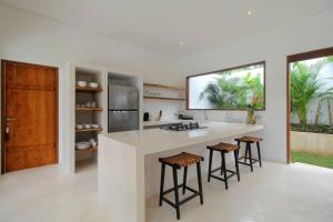 une cuisine avec un comptoir blanc et des tabourets dans l'établissement Modern and stylish 3 Bedroom Villa, à Ubud