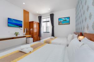 a hotel room with two beds and a tv at Villas & Hotel 126 Vũng Tàu in Vung Tau