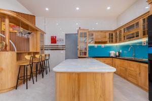 a kitchen with wooden cabinets and a island with bar stools at Villas & Hotel 126 Vũng Tàu in Vung Tau